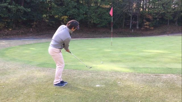 Golfers practice chip and pitch shots around the practice green.