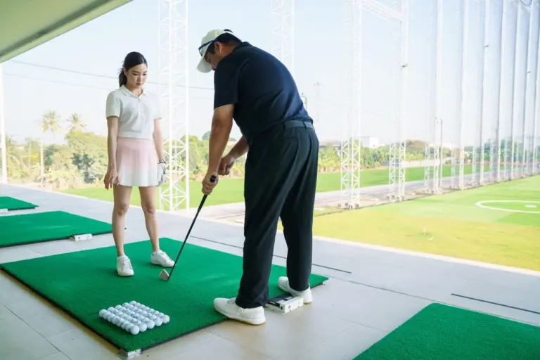 Beginner golfers practice swing fundamentals during an early driving range lesson.