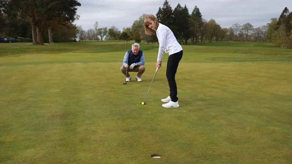 Golfers follow etiquette rules while waiting near the putting green.